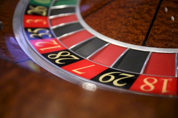 The image shows a close-up of a roulette wheel with numbered red and black slots. Numbers visible include 18, 29, 7, and 28.